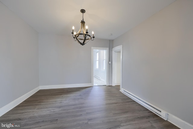 empty room featuring a notable chandelier, baseboard heating, dark wood-type flooring, and baseboards