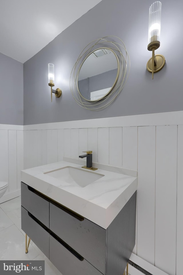 bathroom featuring a wainscoted wall, toilet, marble finish floor, and vanity