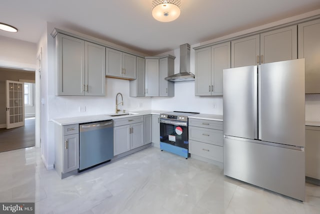 kitchen featuring gray cabinetry, stainless steel appliances, wall chimney exhaust hood, and a sink