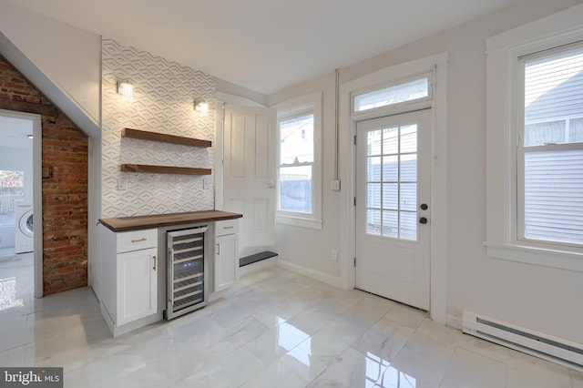 kitchen featuring beverage cooler, open shelves, washer / clothes dryer, wood counters, and a baseboard heating unit