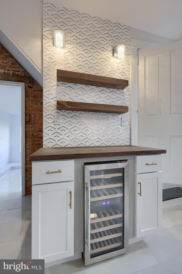 bar featuring a bar, light tile patterned floors, beverage cooler, and brick wall