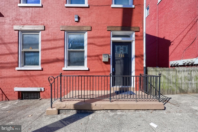 entrance to property featuring brick siding and fence