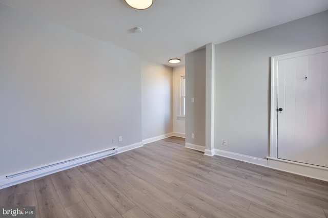 spare room featuring wood finished floors, baseboards, and a baseboard radiator