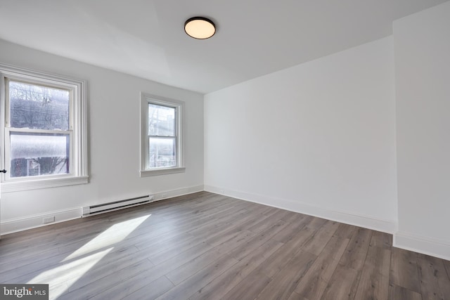 unfurnished room with plenty of natural light, wood finished floors, baseboards, and baseboard heating