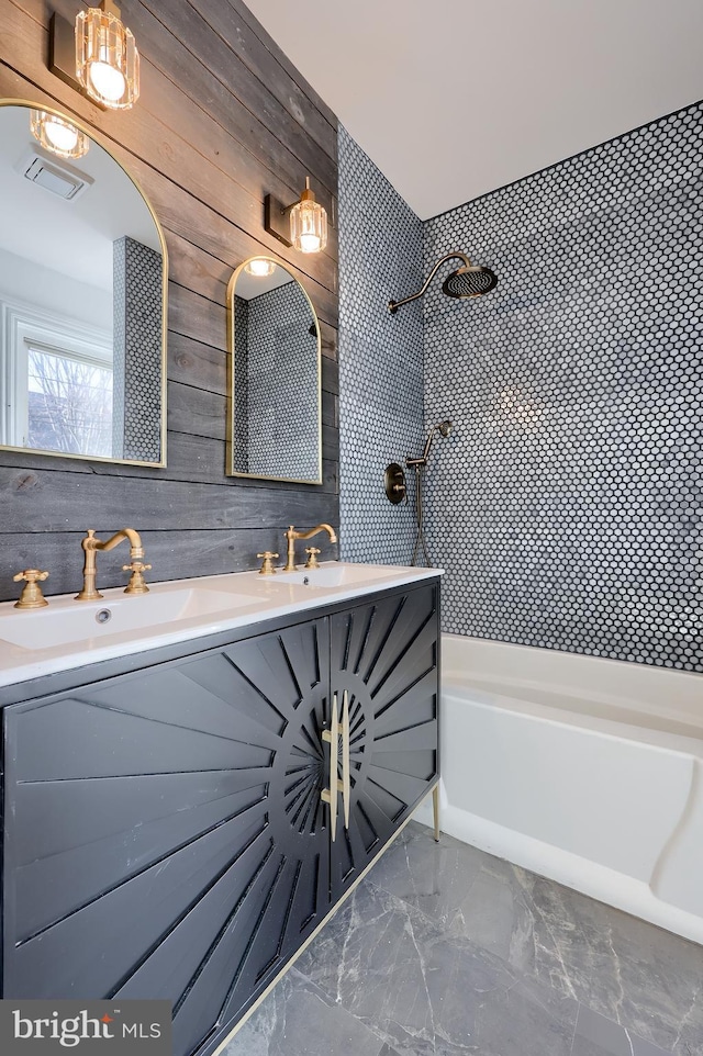 full bathroom with visible vents, marble finish floor, a sink, wooden walls, and double vanity