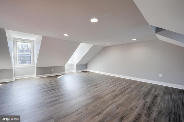 additional living space featuring vaulted ceiling, dark wood-style floors, and baseboards