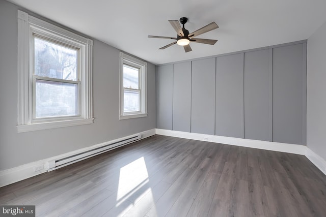 spare room with ceiling fan, baseboards, baseboard heating, and wood finished floors