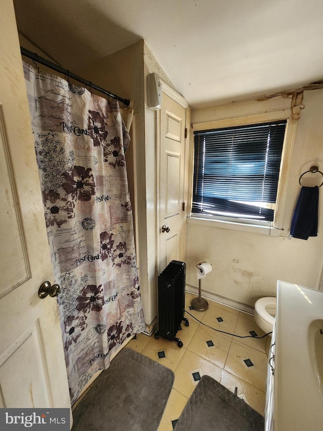 full bath with a shower with curtain, toilet, radiator heating unit, tile patterned flooring, and baseboards