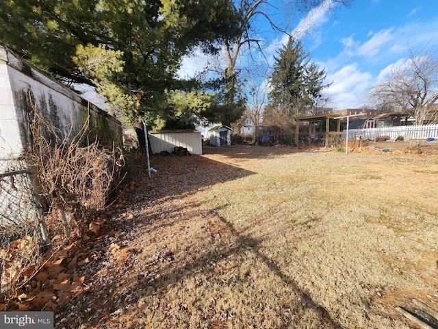 view of yard featuring a storage shed, fence, and an outbuilding