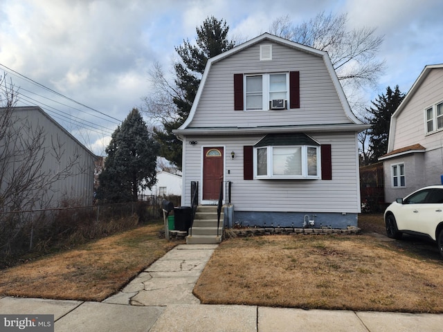 dutch colonial with a gambrel roof, a front lawn, and fence