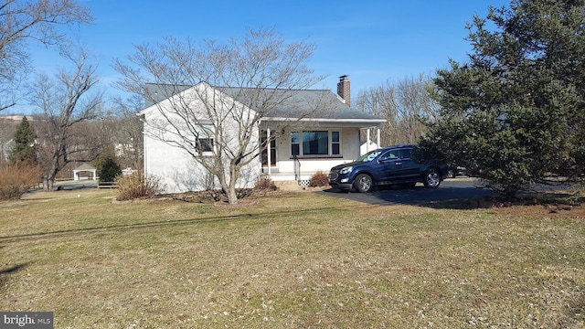 view of front of property featuring stucco siding, a chimney, and a front lawn