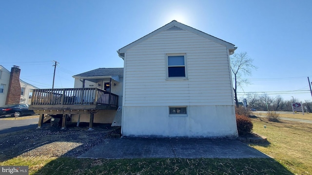 view of side of property with a lawn and a wooden deck