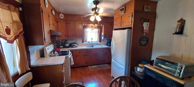 kitchen featuring a sink, white appliances, brown cabinets, and light countertops