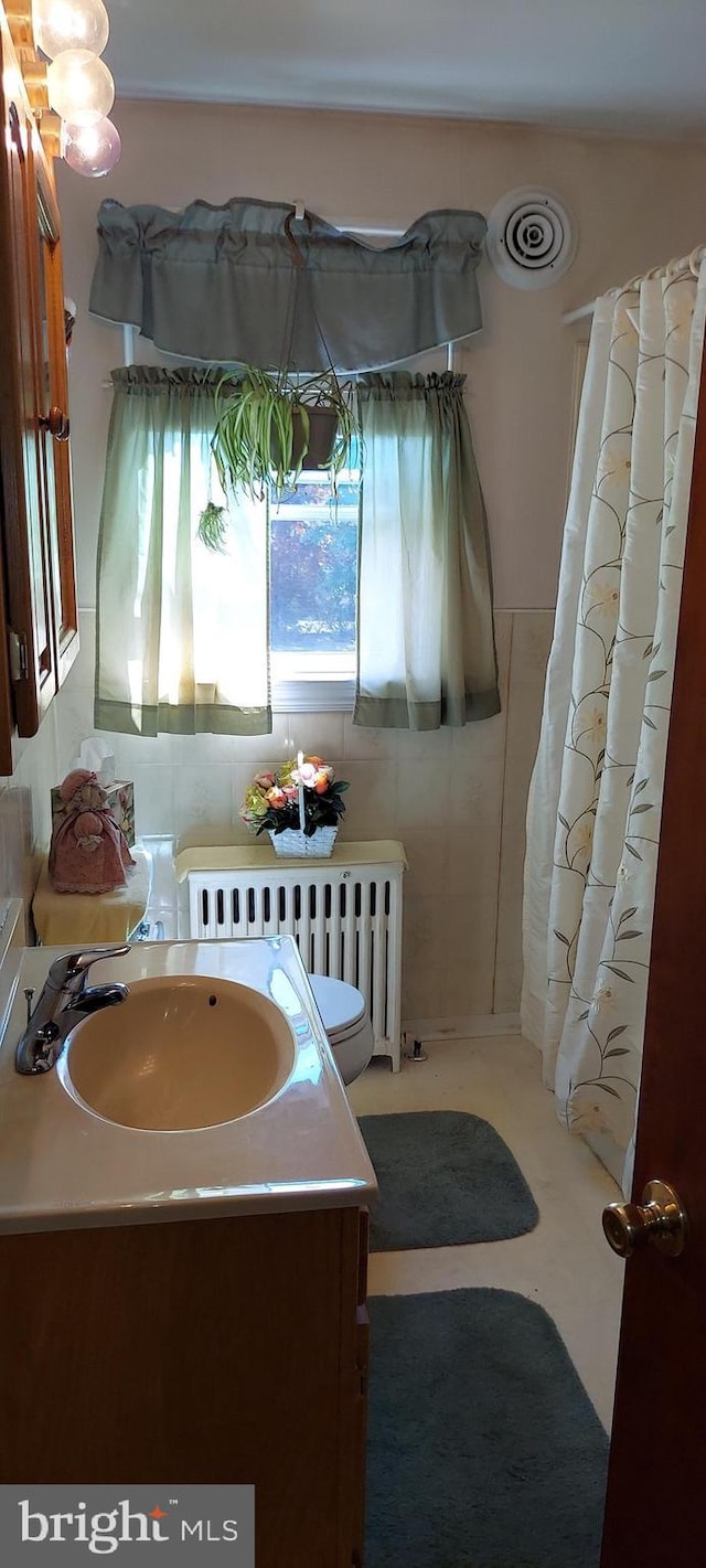 full bathroom with radiator and vanity