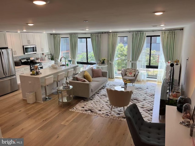 living room featuring a wealth of natural light, light wood-type flooring, and recessed lighting