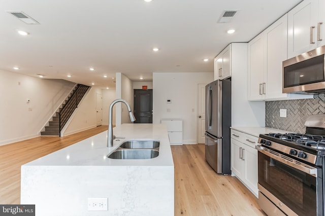 kitchen featuring visible vents, appliances with stainless steel finishes, white cabinetry, and a sink
