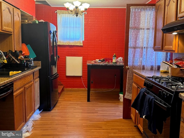 kitchen featuring a sink, black appliances, brown cabinetry, and light wood finished floors