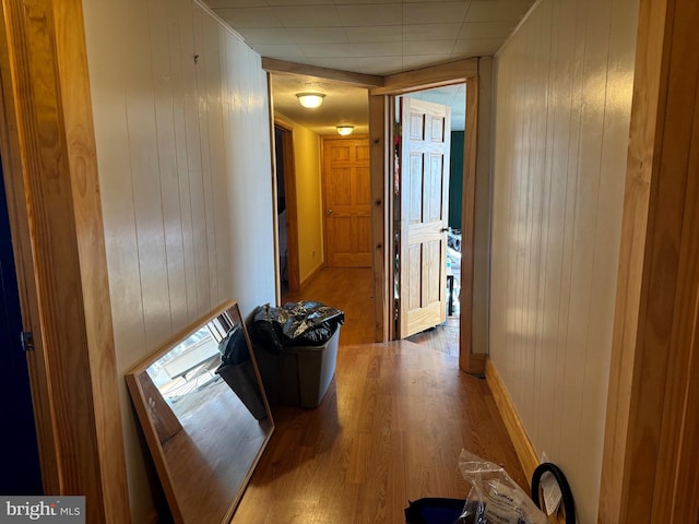 corridor featuring wood finished floors and wood walls