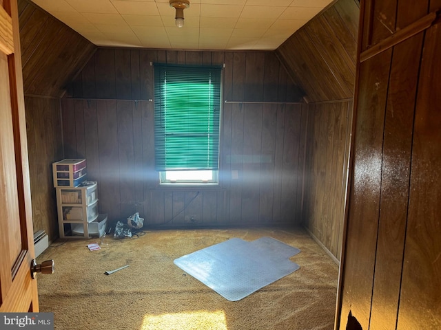 bonus room with a baseboard heating unit, lofted ceiling, and wood walls