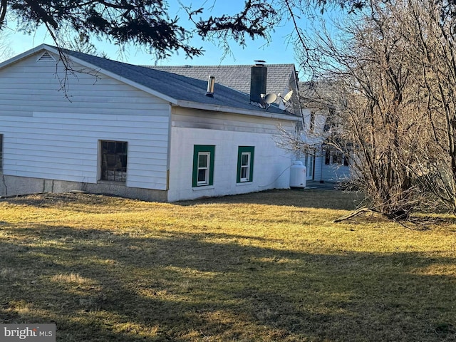 view of side of home with a lawn and a chimney