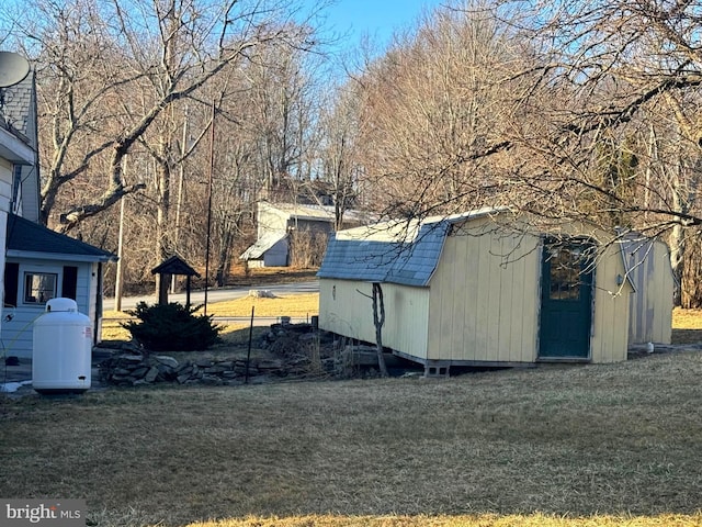 view of side of property with a storage unit, a lawn, a shingled roof, and an outdoor structure