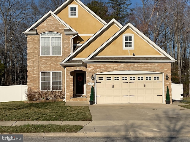 traditional-style home featuring stucco siding, brick siding, driveway, and fence