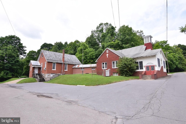 view of front of home with a front yard, brick siding, and a chimney