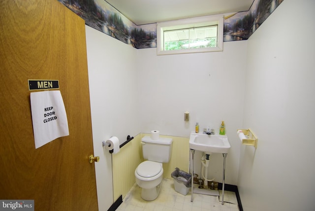 half bath with tile patterned floors, toilet, and a sink