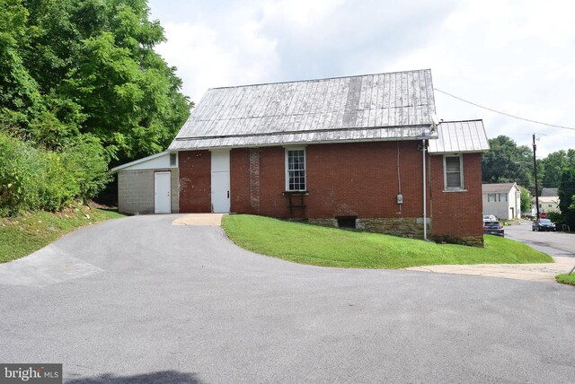 view of property exterior featuring a yard, brick siding, and metal roof