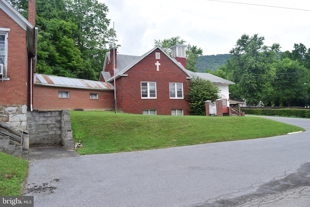 view of side of home featuring a yard, brick siding, and metal roof