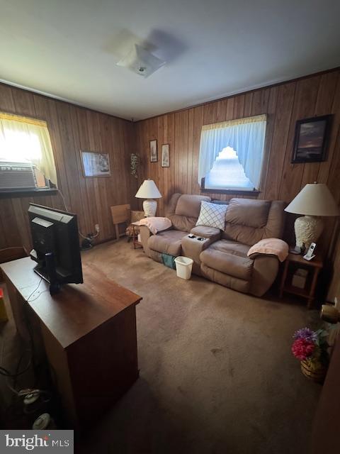 living area with wooden walls, cooling unit, and light colored carpet