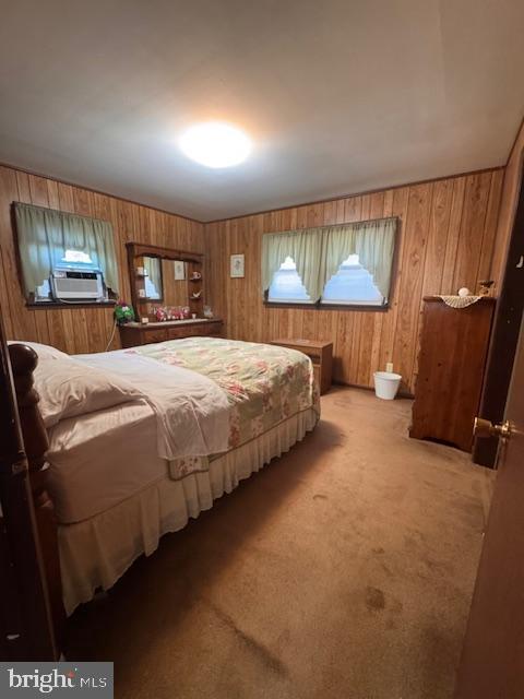 bedroom featuring light carpet, wooden walls, and cooling unit