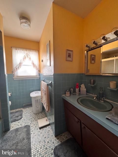 bathroom with tile patterned flooring, a wainscoted wall, vanity, and tile walls