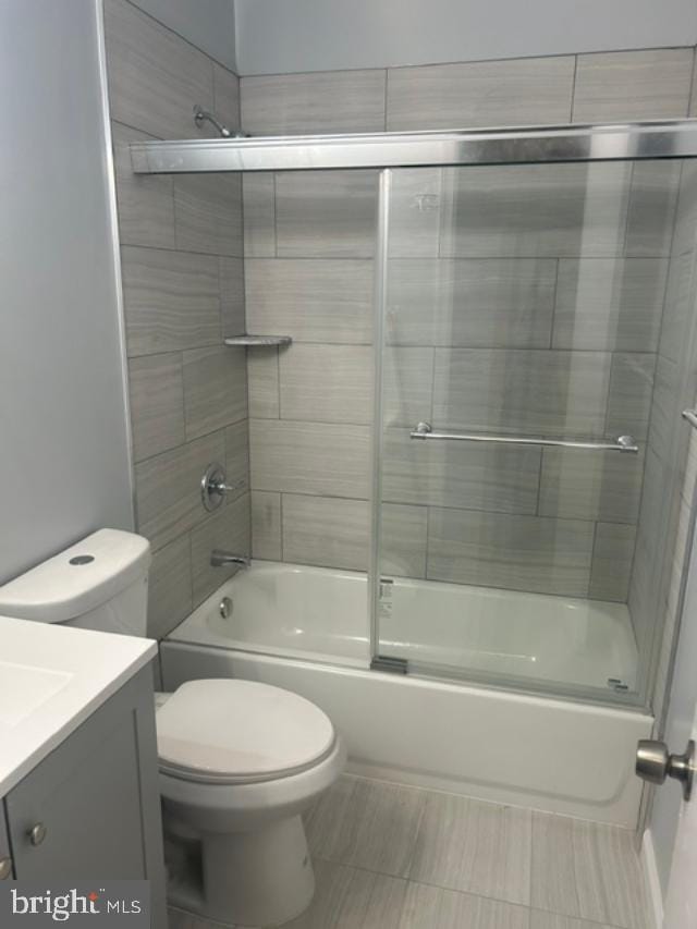 bathroom featuring combined bath / shower with glass door, toilet, and vanity