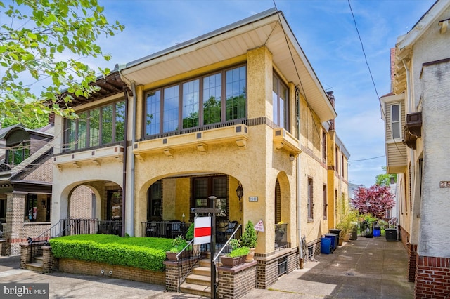 view of front of home with stucco siding, covered porch, and central AC unit