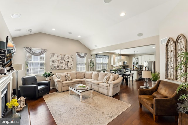 living area featuring visible vents, plenty of natural light, dark wood finished floors, and vaulted ceiling