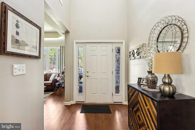 entryway featuring dark wood-style flooring, baseboards, and a towering ceiling