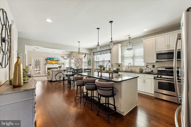 kitchen featuring dark wood-style flooring, dark countertops, a breakfast bar area, a sink, and stainless steel appliances