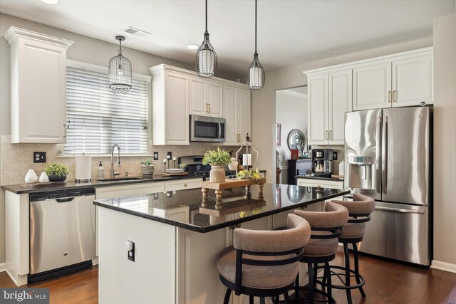 kitchen featuring a sink, appliances with stainless steel finishes, a kitchen island, and tasteful backsplash