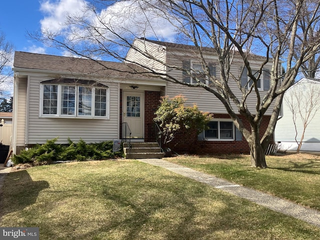 tri-level home featuring brick siding and a front yard