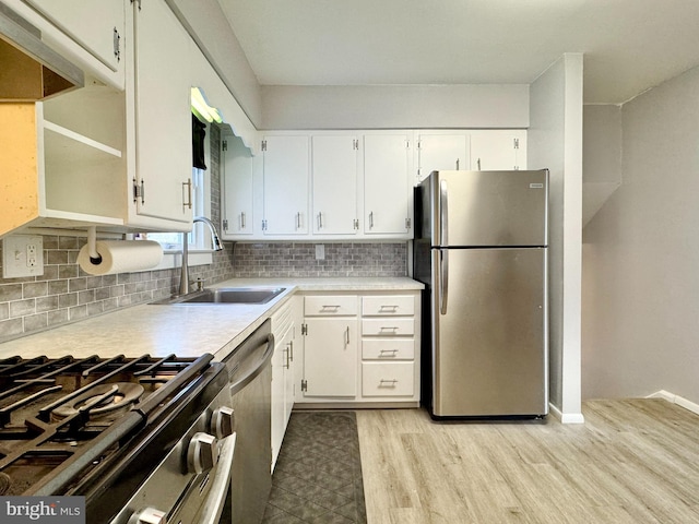 kitchen featuring light countertops, decorative backsplash, light wood-style floors, stainless steel appliances, and a sink