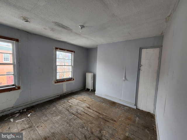 spare room featuring a textured ceiling, radiator, and hardwood / wood-style flooring