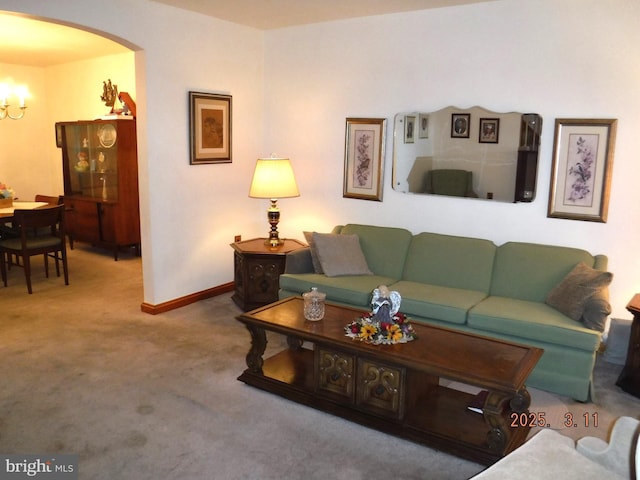 living room with baseboards, carpet floors, arched walkways, and a notable chandelier