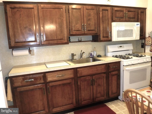 kitchen featuring a sink, decorative backsplash, white appliances, and light countertops