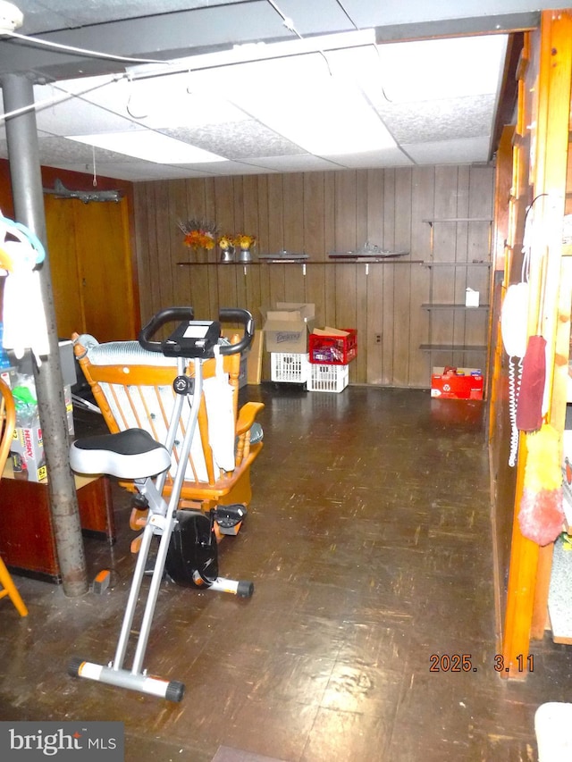 finished basement featuring a drop ceiling and wooden walls