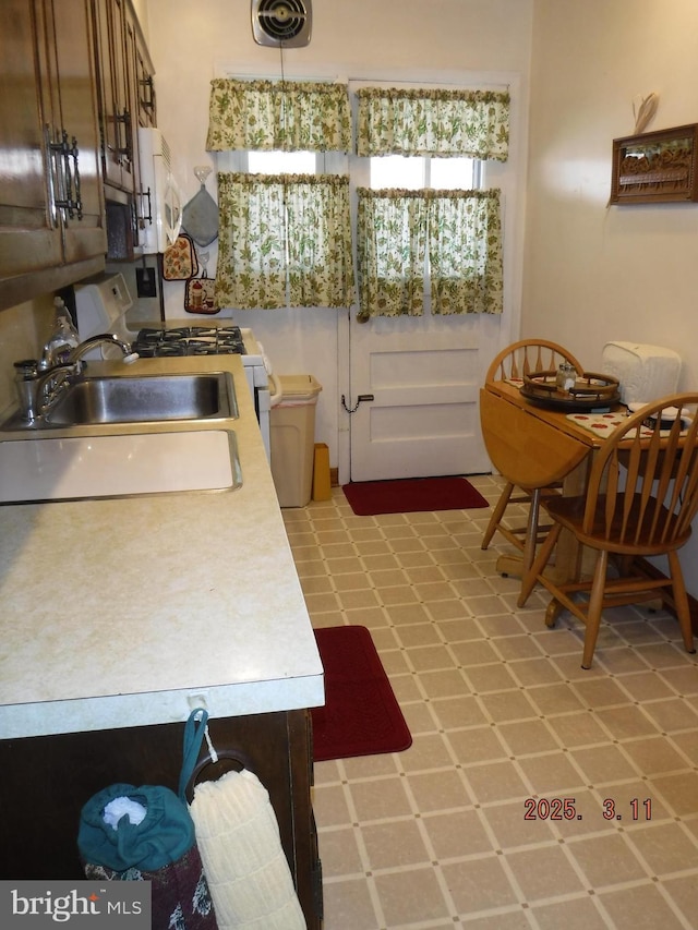 kitchen with visible vents, light floors, light countertops, white appliances, and a sink