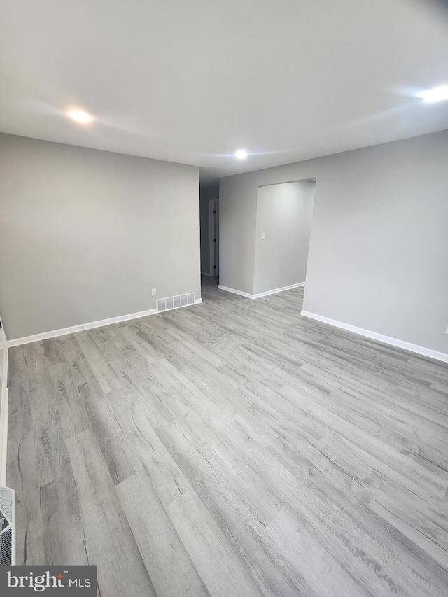 empty room with visible vents, light wood-style flooring, and baseboards