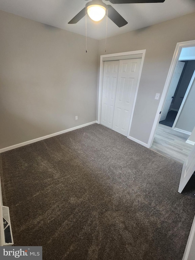 unfurnished bedroom featuring carpet, baseboards, a closet, and ceiling fan