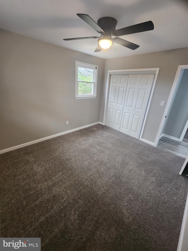 unfurnished bedroom with a closet, baseboards, carpet floors, and a ceiling fan