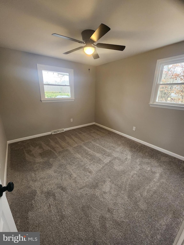 carpeted empty room featuring plenty of natural light, visible vents, baseboards, and a ceiling fan